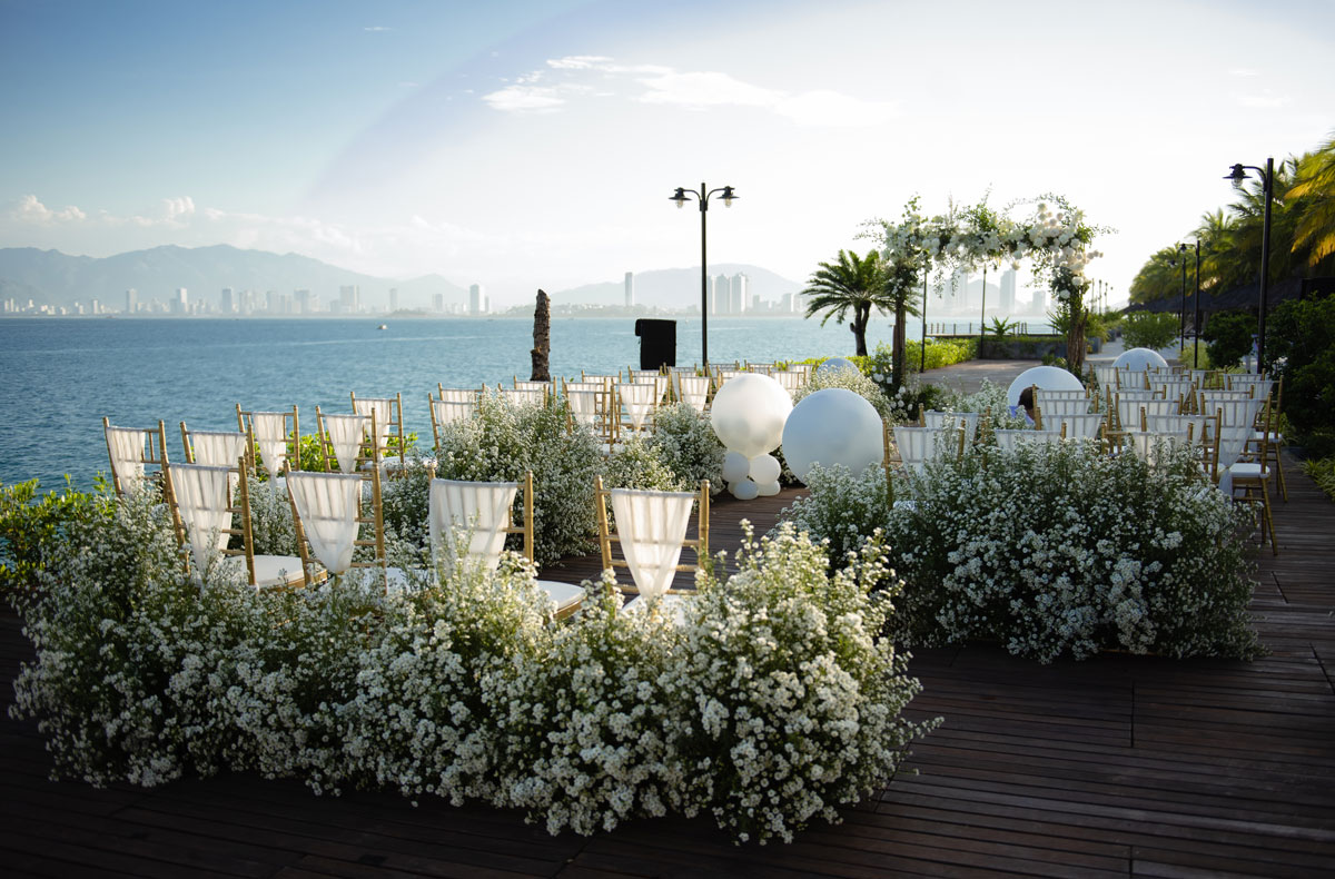 Rustic wooden arch with white flowers on a timber deck over the bay at Amiana Resort, gold chairs and baby's breath Rustic wooden arch with white flowers on a timber deck over the bay at Amiana Resort, gold chairs and baby's breath