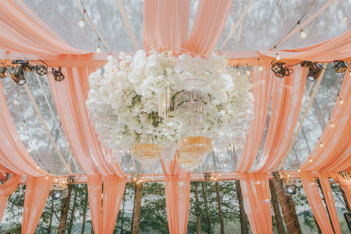 Clear-roof marquee with peach chiffon swags, a white orchid ring and crystal chandeliers in Dalat Clear-roof marquee with peach chiffon swags, a white orchid ring and crystal chandeliers in Dalat
