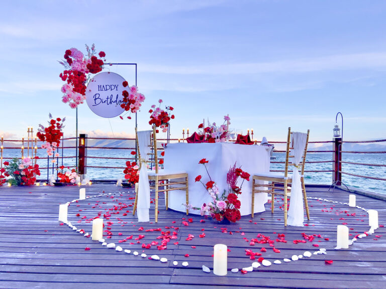Trang Trí Sinh Nhật Nha Trang: Bãi Biển, Resort, Tại Nhà Trang trí sinh nhật Nha Trang bàn đôi rải cánh hoa hồng hoàng hôn cạnh biển, nến LED trong vòng sỏi trắng