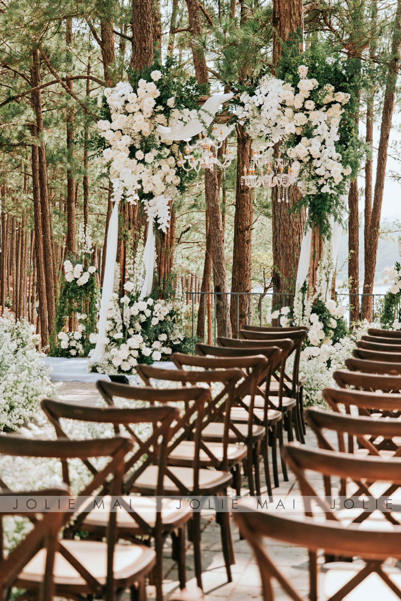 Cross-back chairs facing the flower arch among tall pines at Terracotta Resort Cross-back chairs facing the flower arch among tall pines at Terracotta Resort