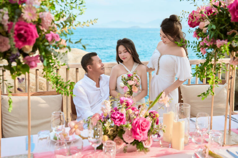 Trang Trí Sinh Nhật Nha Trang: Bãi Biển, Resort, Tại Nhà Chủ tiệc sinh nhật ngồi cạnh bàn có tháp hoa hồng cao, biển Ninh Vân phía sau