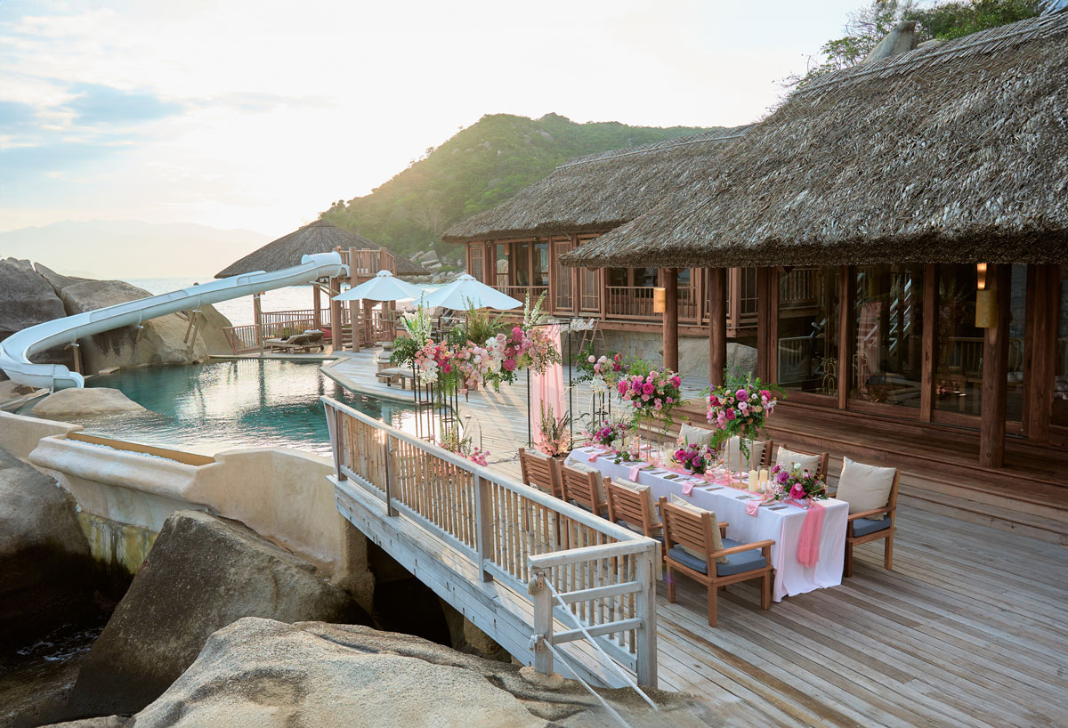 Trang Trí Sinh Nhật Nha Trang: Bãi Biển, Resort, Tại Nhà Trang trí sinh nhật Nha Trang: bàn tiệc sinh nhật dưới mái lá cạnh hồ nước và đá lớn ở resort Six Senses Ninh Vân Bay