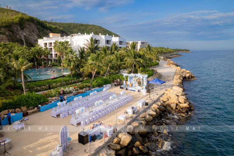 Trang Trí Sinh Nhật Nha Trang: Bãi Biển, Resort, Tại Nhà Bãi tiệc sinh nhật bên bờ đá cạnh hồ bơi Alibu Resort nhìn từ cao, hai dãy bàn và backdrop cuối bãi