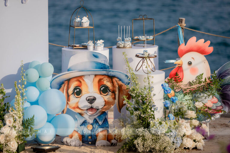 Trang Trí Sinh Nhật Nha Trang: Bãi Biển, Resort, Tại Nhà Bàn dessert với standee chú chó đội mũ xanh và chú gà trống bên bờ biển