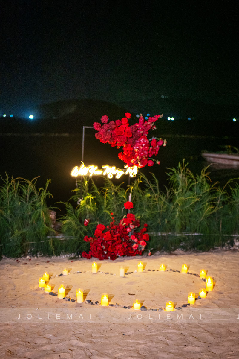 Chữ neon Will You Marry Me và trái tim nến LED trên cát lúc trời tối Chữ neon Will You Marry Me và trái tim nến LED trên cát lúc trời tối