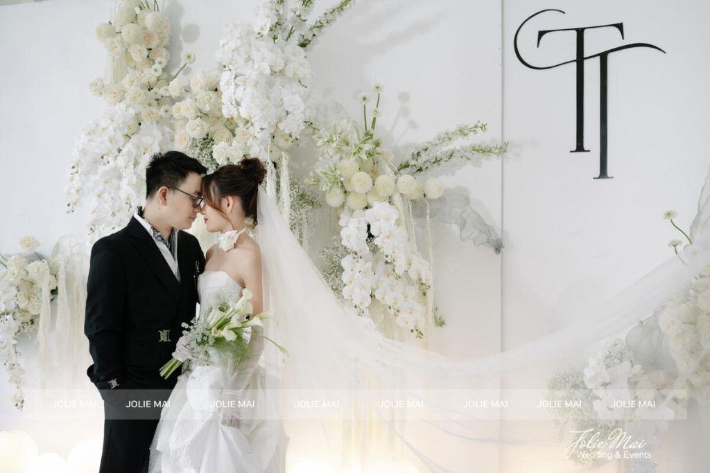 Hoa Cầm Tay Cô Dâu Nên Chọn Hoa Gì: Theo Váy Và Bảng Màu Hoa cầm tay cô dâu nên chọn hoa gì: cô dâu váy trắng cầm bó calla trắng, hợp bảng màu trắng xanh của backdrop