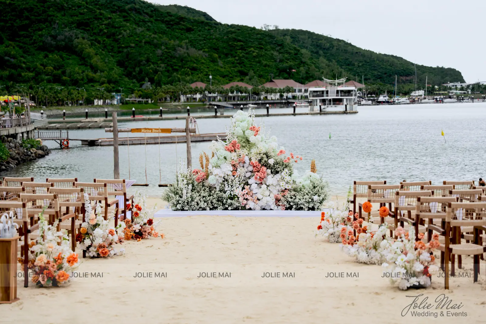Cụm hoa tròn lớn trên thảm trắng, cẩm tú cầu trắng phối san hô và cỏ khô, hai dãy ghế gỗ Cụm hoa tròn lớn trên thảm trắng, cẩm tú cầu trắng phối san hô và cỏ khô, hai dãy ghế gỗ