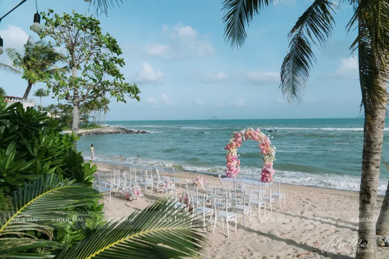 Quay Chụp Phóng Sự Cưới Nha Trang: Một Đầu Mối Từ Trang Trí Đến Thước Phim Cổng vòm hoa hồng giữa hàng dừa và biển, ghế trắng xếp dọc lối đi trong lễ cưới ngoài trời