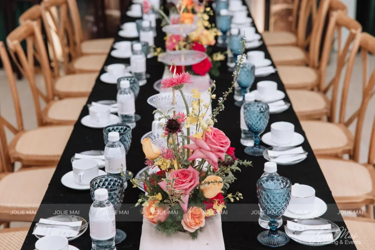 Dịch Vụ Cưới Nha Trang Một Đầu Mối: Gia Tiên, Tiệc, Mâm Quả Bàn dài khăn nhung đen chạy chỉ trắng, bình hoa hồng cam giữa bàn, ly pha lê xanh và tách trắng viền vàng