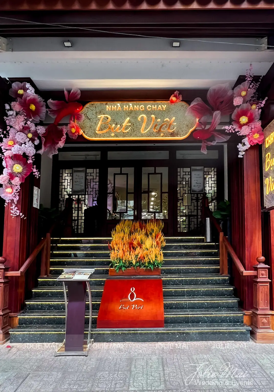 Mặt tiền nhà hàng chay Bụt Việt trang trí Tết bằng hoa vải hồng đỏ và cá organza Mặt tiền nhà hàng chay Bụt Việt trang trí Tết bằng hoa vải hồng đỏ và cá organza