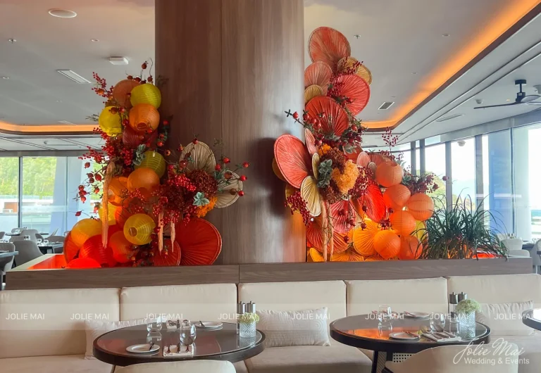 Trang Trí Tiệc Nha Trang: Sinh Nhật, Kỷ Niệm, Tất Niên Và Giáng Sinh Cột gỗ nhà hàng ốp quạt giấy tròn, đèn lồng cam vàng và hoa mùa Tết cạnh dãy sofa