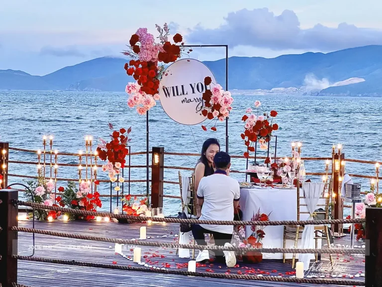 Trang Trí Tiệc Nha Trang: Sinh Nhật, Kỷ Niệm, Tất Niên Và Giáng Sinh Bàn tối hai người trên bến gỗ ven biển, bảng Will You Marry Me phủ hoa hồng đỏ và hàng nến hai bên