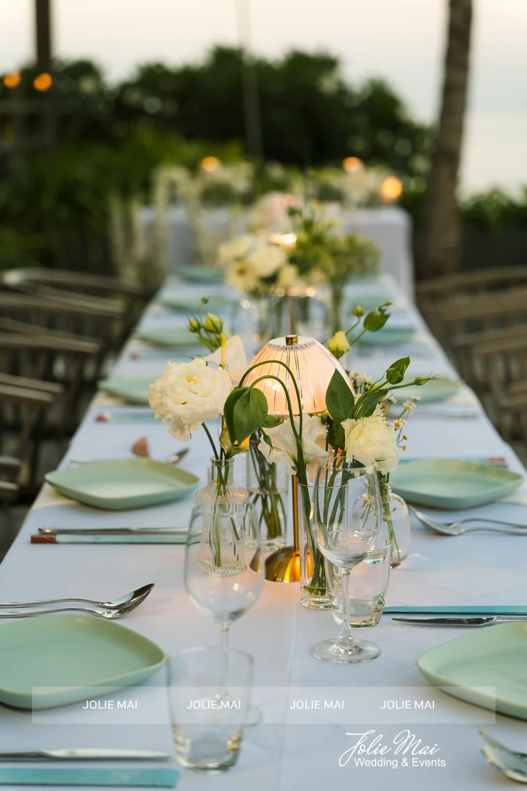 Sunset long table with white flowers, glass lamps and mint plates at Mia Resort Nha Trang Sunset long table with white flowers, glass lamps and mint plates at Mia Resort Nha Trang
